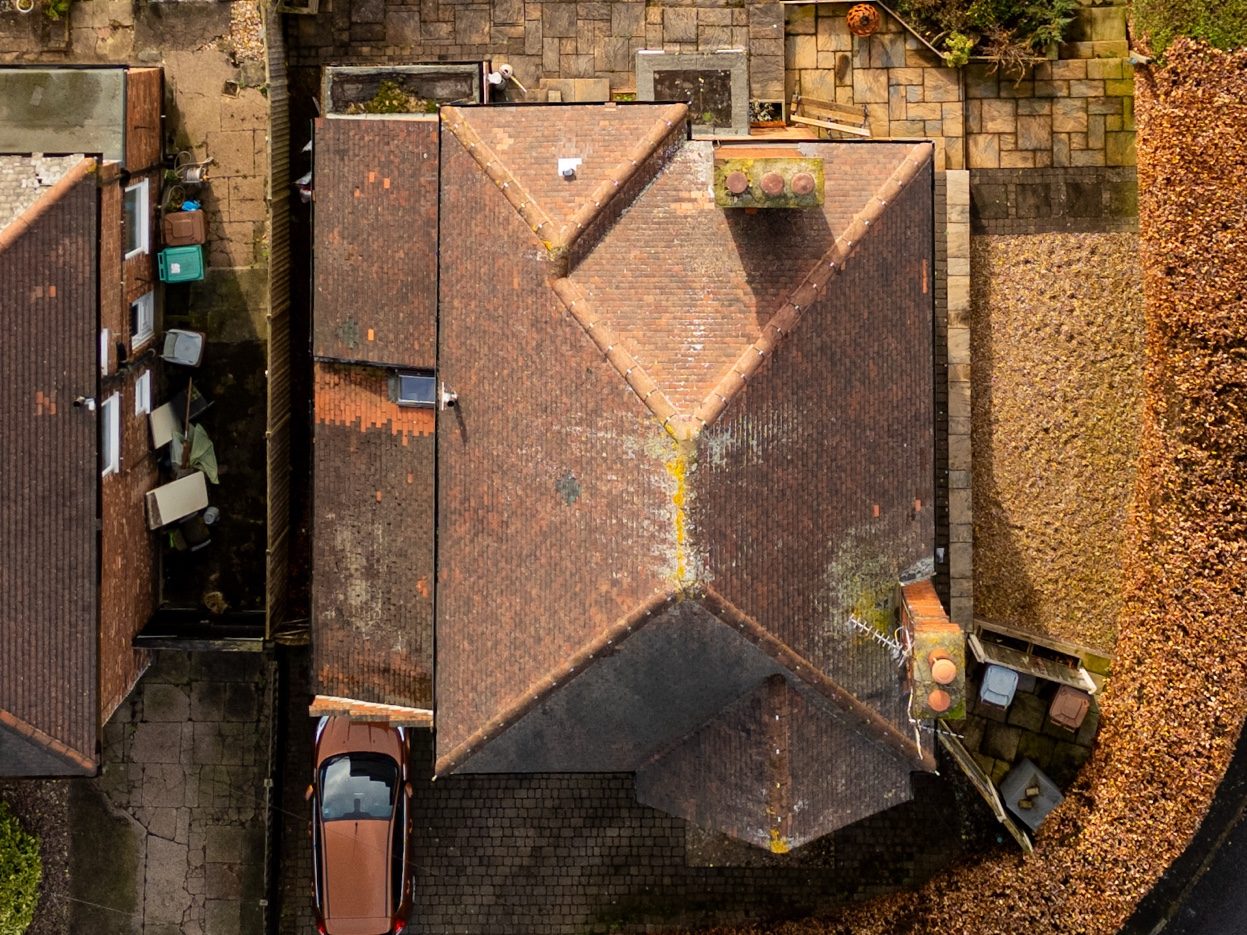 Aerial drone view of complex roof showing lichen growth and wear assessed during roof survey